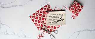 A Lifestyle image of the fabric scissors zipper pouch shown styled with wrapping paper, ribbon, and scissors on a quartz background.