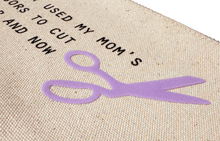 A close up view of the canvas zip pouch with the fabric scissors saying and lavender PUFF ink.