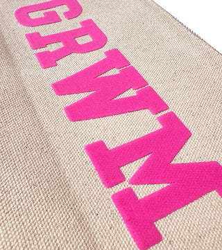 A close-up view of the "GRWM" canvas zip pouch in pink puff ink.