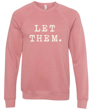 Pink sweatshirt with 'Let them.' text printed in cream ink.