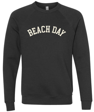 Black colored sweatshirt with 'BEACH DAY' text printed in cream ink. 