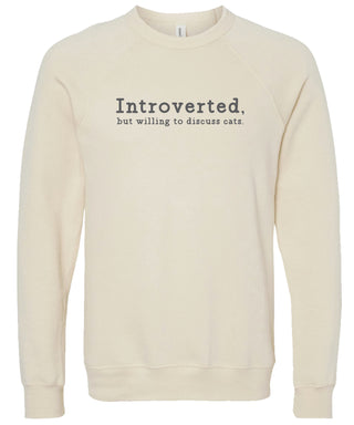 Cream sweatshirt with text 'Introverted, but willing to discuss cats' printed in gray ink.