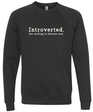 Black sweatshirt with text 'Introverted, but willing to discuss cats' printed in cream ink.