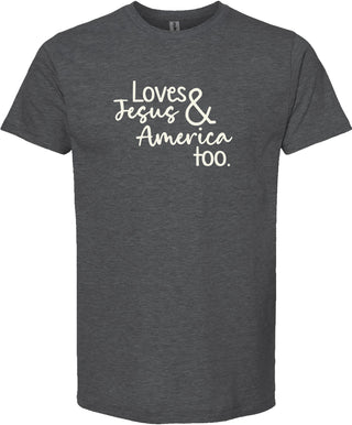 Dark gray t-shirt with text 'Loves Jesus & America too.' printed in cream ink.