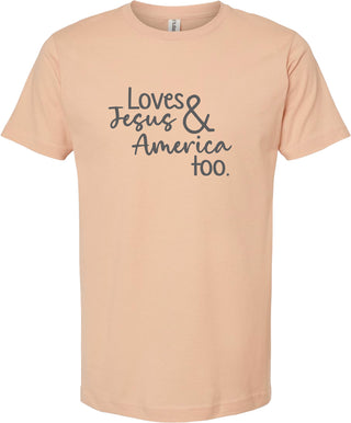Peach t-shirt with text 'Loves Jesus & America too.' printed in gray ink.