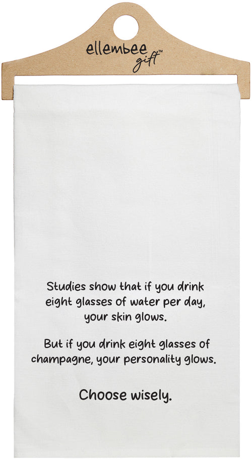 White towel with printed text 'Studies show that if you drink eight glasses of water daily, your skin glows. But if you drink eight glasses of champagne, your personality glows. Choose wisely.' printed in black ink.