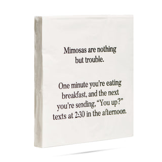 A side view of a pack of white 3-ply cocktail napkins printed in black with "Mimosas are nothing but trouble. One minute you're eating breakfast, and the next you're sending You up? texts at 2:30 in the afternoon."