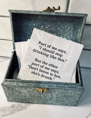 A lifestyle shot of a white 3-ply cocktail napkin printed in black with "Part of me says, I should stop drinking like this. But the other part of me says, don't listen to her, she's drunk."