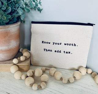 The know your worth zipper pouch shown styled with  a plant and a string of decorative beads.