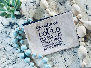 Lifestyle shot of the "she believed she could" canvas zipper pouch.