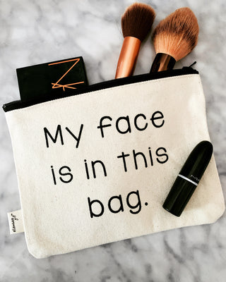 The my face is in this bag makeup bag shown styled with cosmetics and beauty essentials.