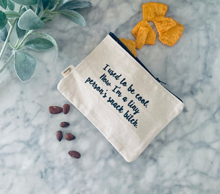 Lifestyle shot of the "snack bitch" canvas zipper pouch.